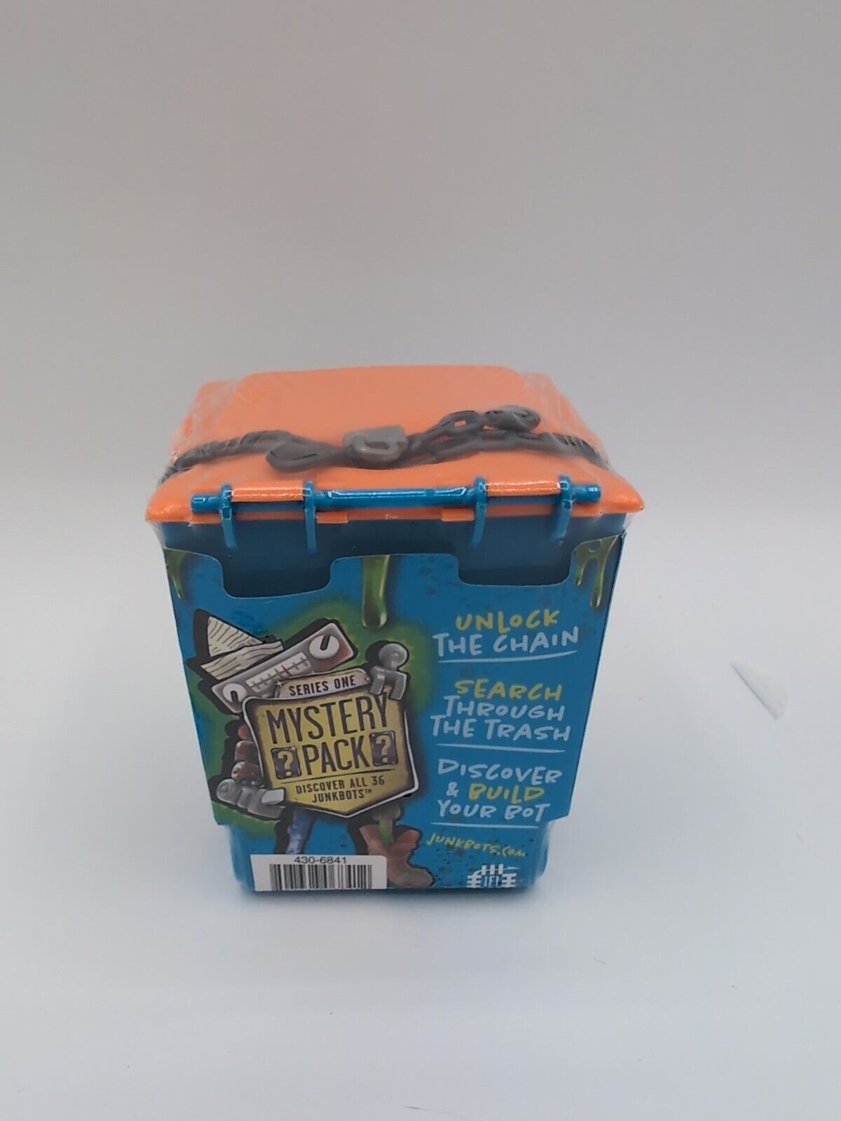 A HEXBUG JUNK BOTS action figure set in a Trash Bin Assortment Kit, packaged in an orange and blue box with a military and adventure theme design.